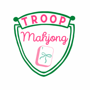 Pink, green, and white crest reading Troop Mahjong in pink lettering with a sketch of a mahjong tile