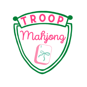 Pink, green, and white crest reading Troop Mahjong in pink lettering with a sketch of a mahjong tile